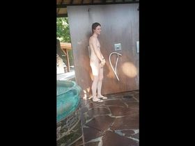 На нудистском пляже телка моется под душем не замечая парня с камерой